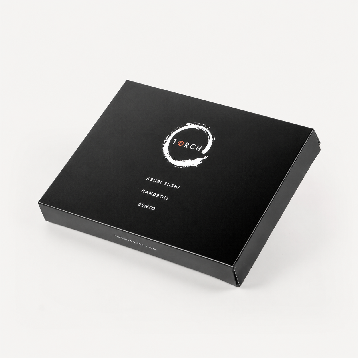 Closed black Torch Sushi bento box angled against a seamless white background, displaying the brand logo and text.