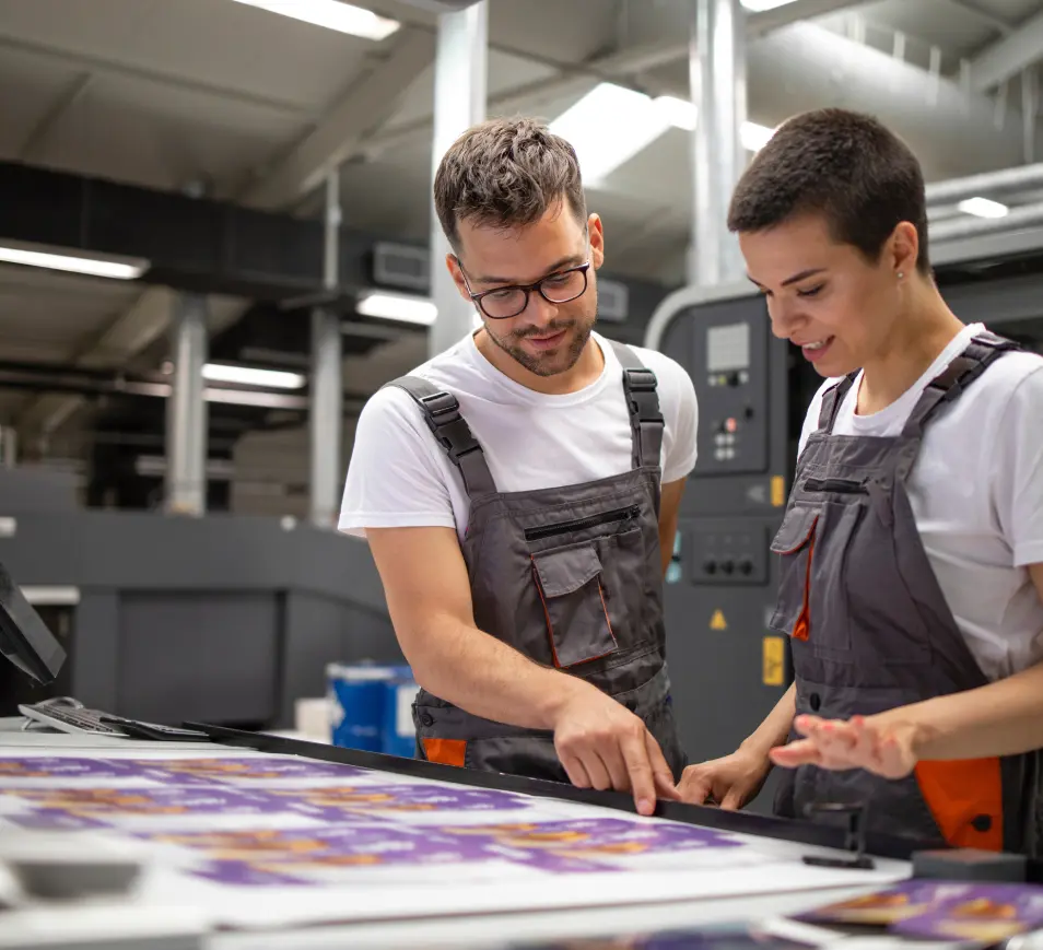 Two press operators checking a printed sheet