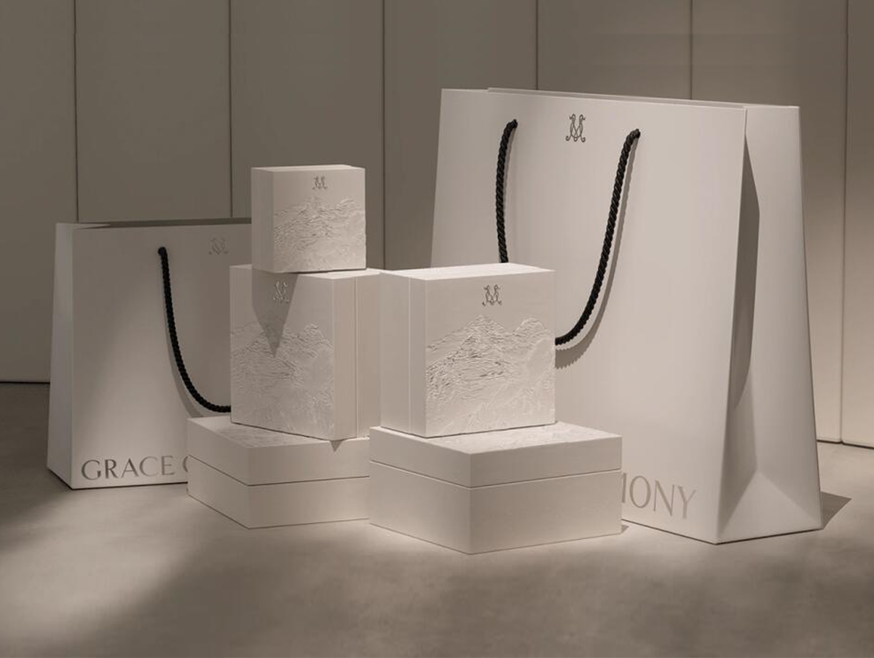 Embossed white gift boxes and shopping bags photographed as a retail packaging set
